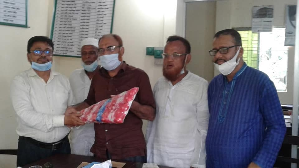 অফিসে পাঁচজন দাঁড়িয়ে; একজনকে ফুলের তোড়া দেওয়া হচ্ছে