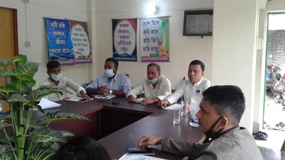 অফিসের সভাকক্ষে টেবিল ঘিরে সভা; দেয়ালে সঞ্চয় নিয়ে পোস্টার